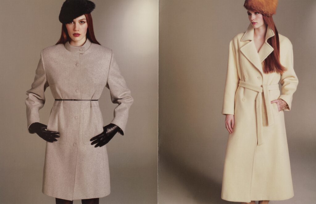 Two models present tailored wool coats in neutral tones, styled with hats and gloves against a minimalist studio backdrop.