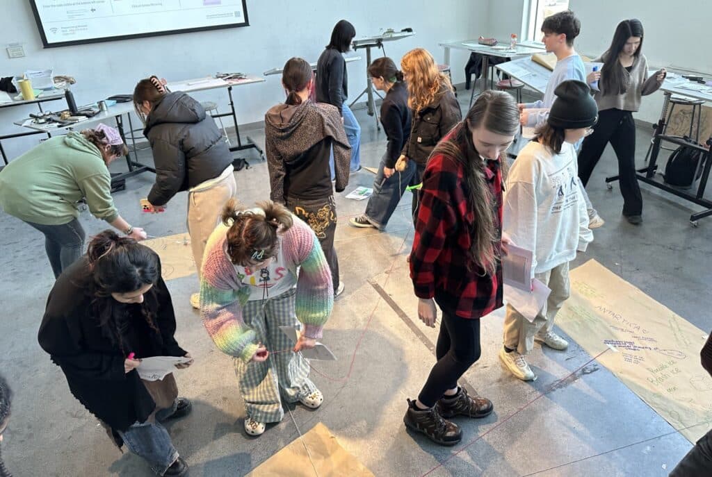 Students move around a classroom connecting ideas with coloured string during an interactive mapping activity.
