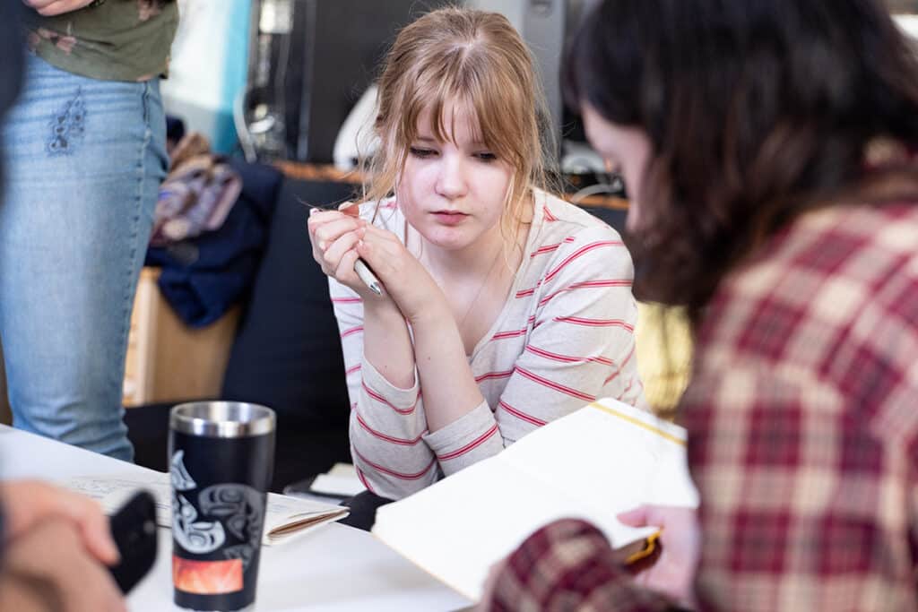 Two participants reviewing notes together across a table during a collaborative planning session.