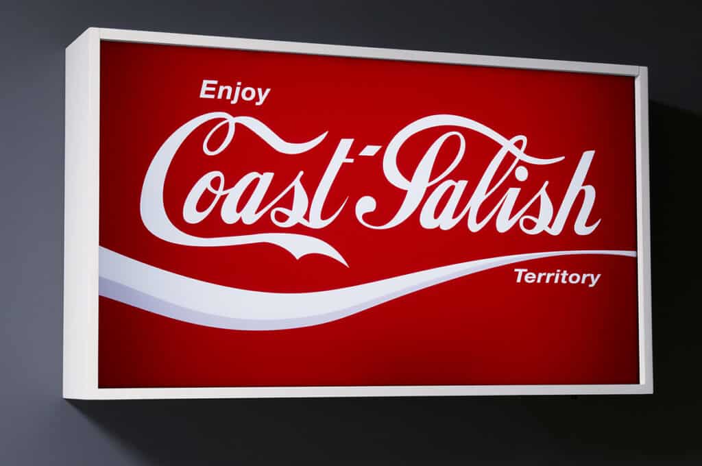 Lightbox artwork styled like a vintage soda advertisement, replacing the familiar logo with the words “Enjoy Coast Salish Territory” in white script on a bright red background.