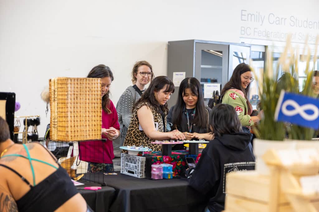 People browsing vendor tables and handmade goods at a busy indoor market.